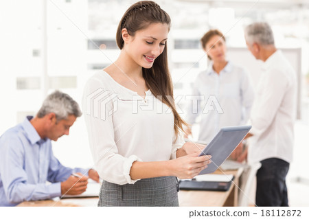 Smiling businesswoman using tablet in a meeting Smiling businesswoman using tablet in a meeting 18112872