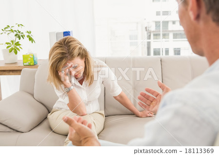 Unhappy woman sitting on couch and talking to therapist 18113369