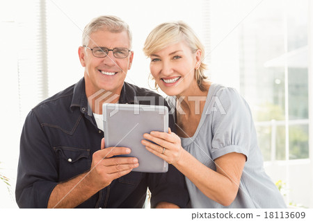 Smiling business team working over a tablet Smiling business team working over a tablet 18113609