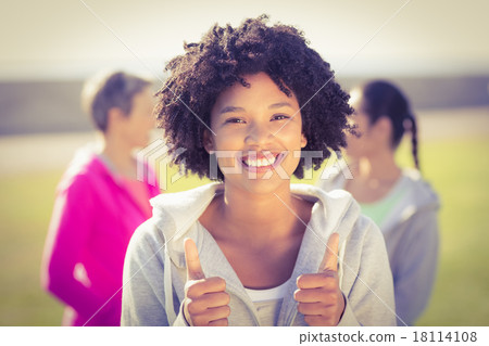 Sporty woman doing thumbs up in front of friends Sporty woman doing thumbs up in front of friends 18114108