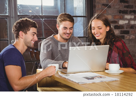 Smiling friends having coffee together and looking at laptop Smiling friends having coffee together and looking at laptop 18114292