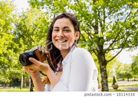 Beautiful brunette taking photo in the park 18114338