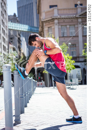 Handsome athlete doing leg stretching on a stake 18114702