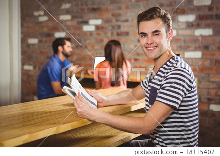 Young man reading a newspaper Young man reading a newspaper 18115402