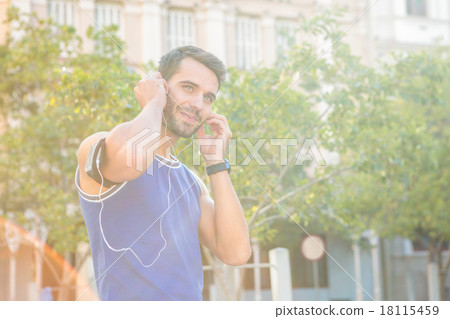 Handsome athlete smiling and putting in headphones Handsome athlete smiling and putting in headphones 18115459