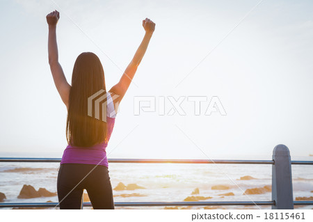 Rear view of fit woman cheering at promenade Rear view of fit woman cheering at promenade 18115461