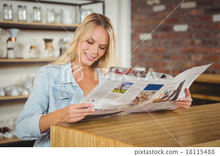 Smiling blonde reading newspaper Smiling blonde reading newspaper 18115488