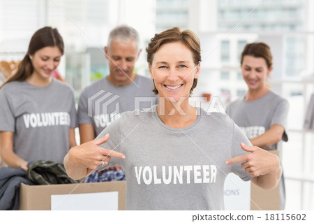 Smiling female volunteer pointing on shirt 18115602