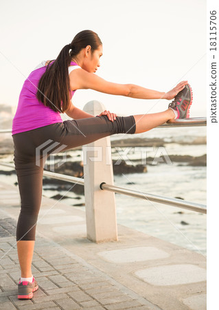 Fit woman stretching leg on railing 18115706