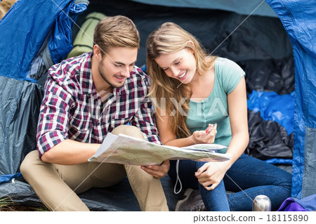 Young pretty hiker couple sitting in a tent looking at map Young pretty hiker couple sitting in a tent looking at map 18115890