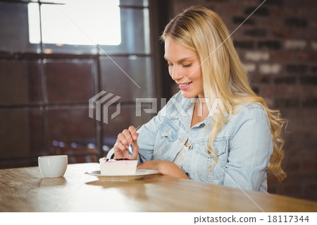 Smiling blonde eating cake and having coffee Smiling blonde eating cake and having coffee 18117344
