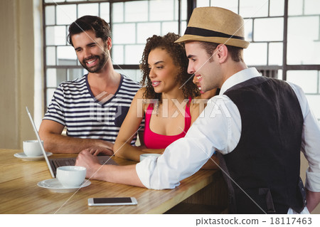 Smiling friends looking at laptop and having coffee 18117463
