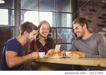 Smiling friends enjoying coffee and croissants together Smiling friends enjoying coffee and croissants together 18117485