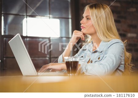 Concentrated blonde having coffee and using laptop Concentrated blonde having coffee and using laptop 18117610