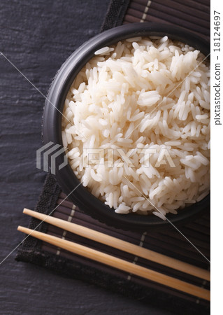 White rice in a black bowl and chopsticks top view White rice in a black bowl and chopsticks top view 18124697