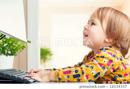 A girl with a smile watching a computer monitor 18134337