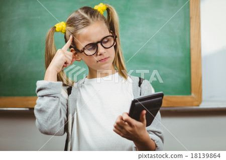Cute pupil calculating with calculator in a classroom Cute pupil calculating with calculator in a classroom 18139864