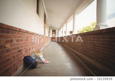 Sad pupil sitting alone on ground 18139939