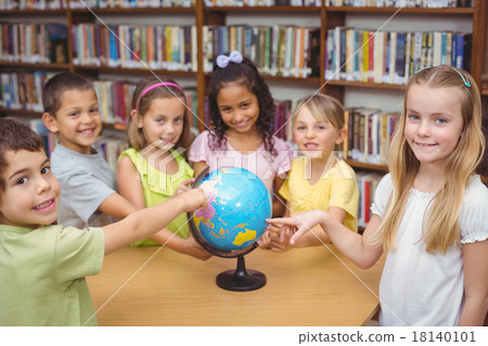 Pupils smiling at camera in library pointing to globe Pupils smiling at camera in library pointing to globe 18140101