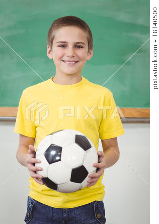 Smiling pupil holding football in a classroom Smiling pupil holding football in a classroom 18140500