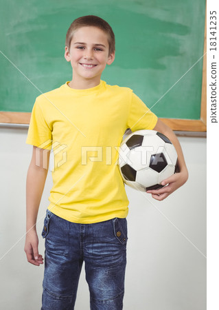 Smiling pupil holding football in a classroom 18141235