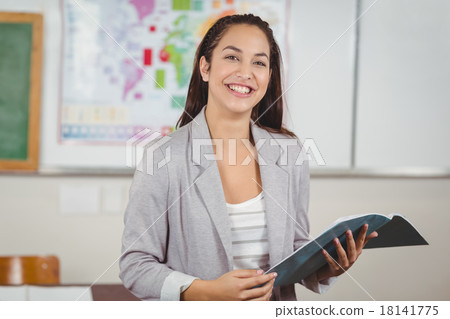 Pretty teacher holding notebook in a classroom 18141775