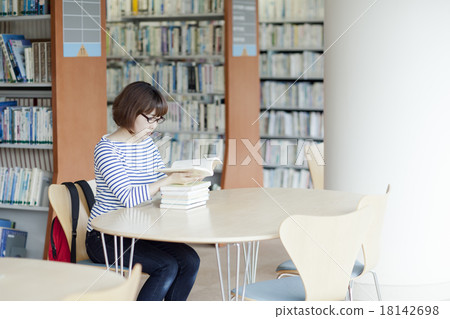 A woman reading a book in a library 18142698