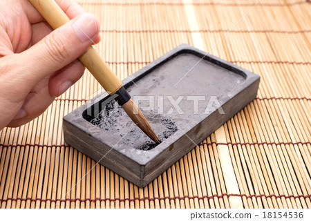 Hand holding Chinese brushes on inkstone 18154536
