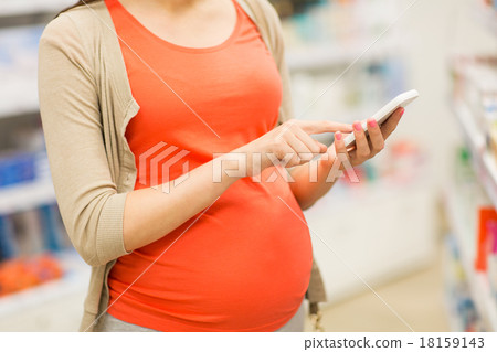 pregnant woman with smartphone at pharmacy pregnant woman with smartphone at pharmacy 18159143
