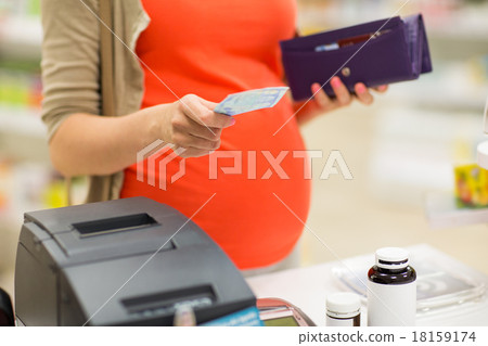 pregnant woman with money at cashbox in drugstore pregnant woman with money at cashbox in drugstore 18159174