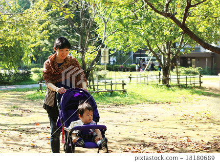 A mother walking in the park with a stroller Baby parent and child A mother walking in the park with a stroller Baby parent and child 18180689