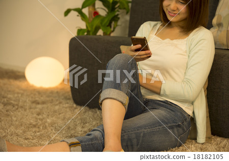A woman watching a smartphone in a room at night A woman watching a smartphone in a room at night 18182105