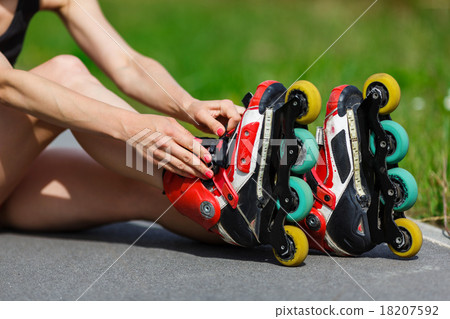 Young girl putting on inline skates Young girl putting on inline skates 18207592
