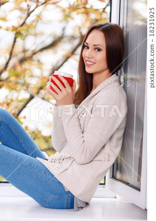 Woman on the windowsill with a cup of drink. 18231925