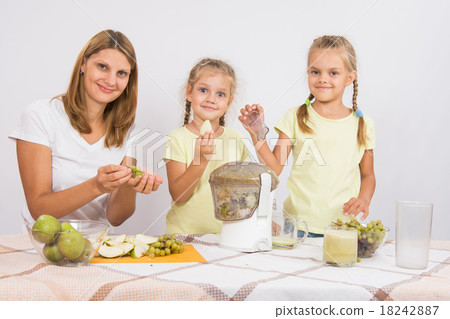 Mother and daughter squeezing juice from pears 18242887