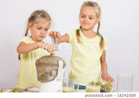 Two girls squeezed juice in a juicer 18242889