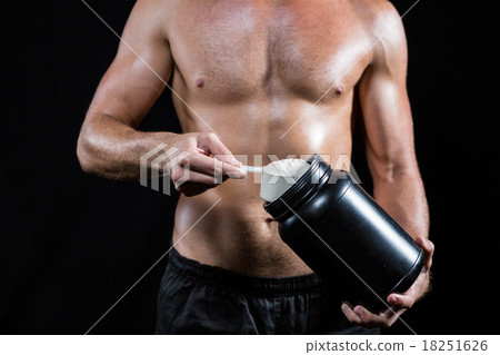 Shirtless man scooping up protein powder Shirtless man scooping up protein powder 18251626