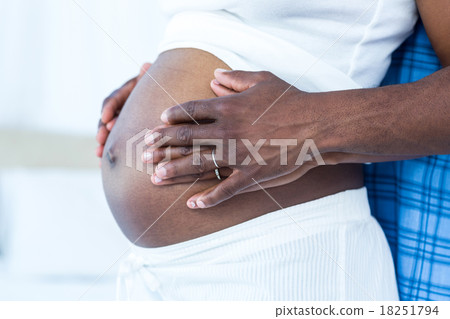 Mid section of husband touching belly of pregnant wife Mid section of husband touching belly of pregnant wife 18251794