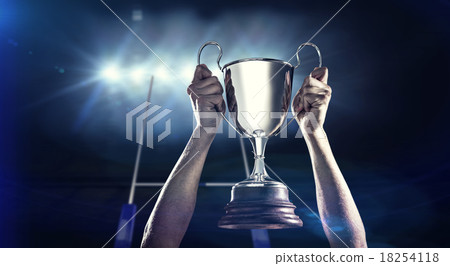 Composite image of successful rugby player holding trophy 18254118