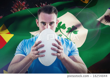 Composite image of rugby player looking at camera with ball 18254844