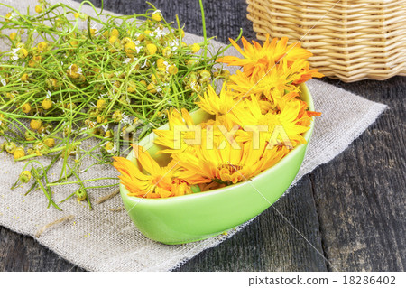 Marigold flowers in bowl with dry chamomile on the 18286402