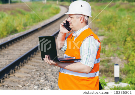 Railway Engineer with smartphone and laptop near r Railway Engineer with smartphone and laptop near r 18286801