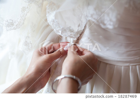Bridesmaid is helping the bride to dress 18287469
