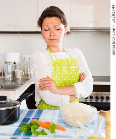 Pensive woman cooks rice with vegetables Pensive woman cooks rice with vegetables 18293744
