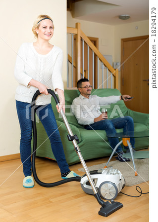 Wife cleaning while husband relaxing 18294179