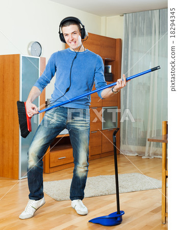 Handsome young man pretending to play guitar with broom Handsome young man pretending to play guitar with broom 18294345