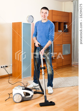 Guy vacuuming with vacuum cleaner on parquet floor Guy vacuuming with vacuum cleaner on parquet floor 18294375