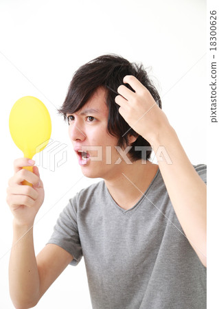 A surprising young man looking at the hairline of his hair 18300626