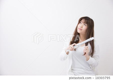 一個女人用發鐵安排她的頭髮 18303795