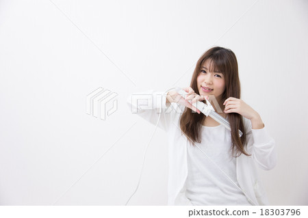 一個女人用發鐵安排她的頭髮 18303796